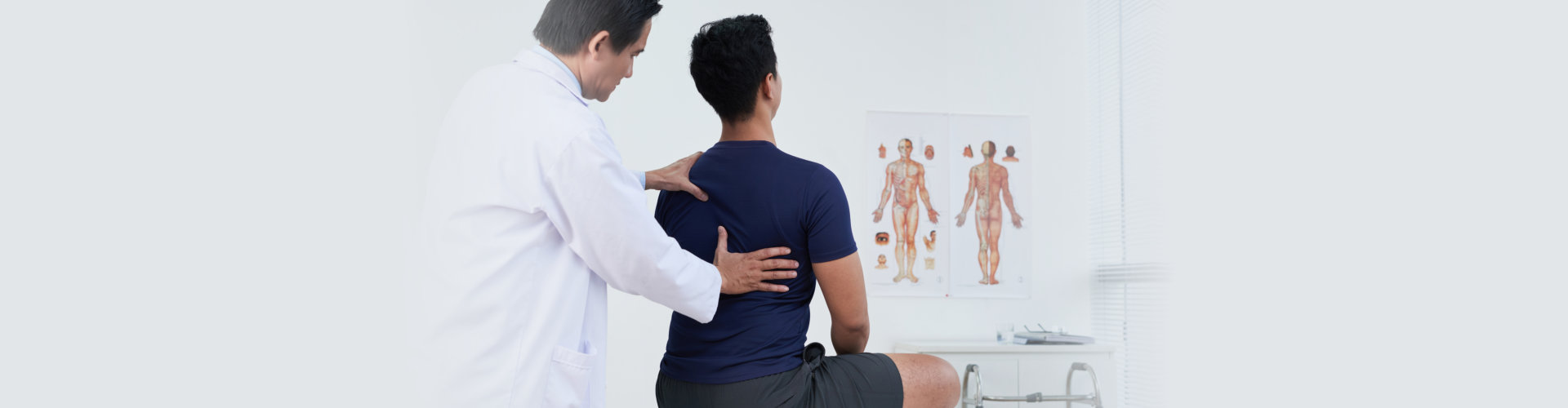 a patient being checked his back by the doctor